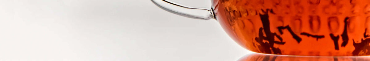 Kinto glass teapot filled with red tea, close-up brand banner