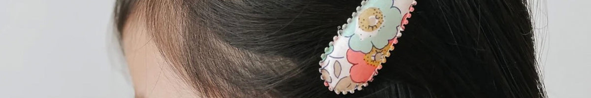 Josie Joan's floral Liberty print hair clip worn in dark hair, brand banner