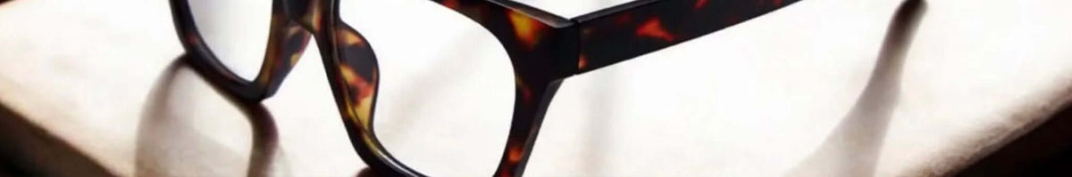Daily Eyewear tortoiseshell reading glasses casting shadows on a white surface, brand banner