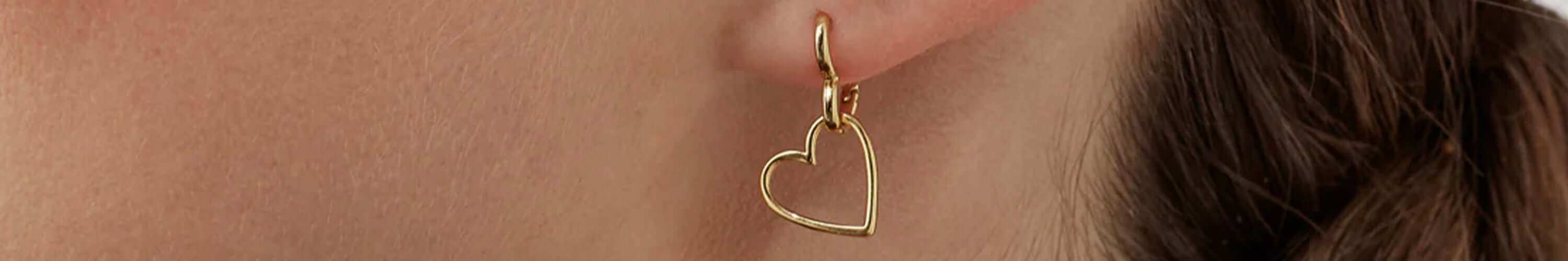 Estella Bartlett gold heart hoop earring close-up on ear, minimalist London jewellery accessory