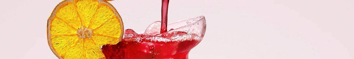 FN Lemons red cocktail being poured into a coupe glass beside a slice of dried orange, brand banner
