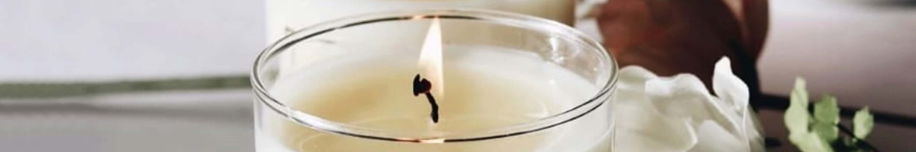 George & Edi Fragrance artisanal soy candle with a lit wick in elegant glass container.