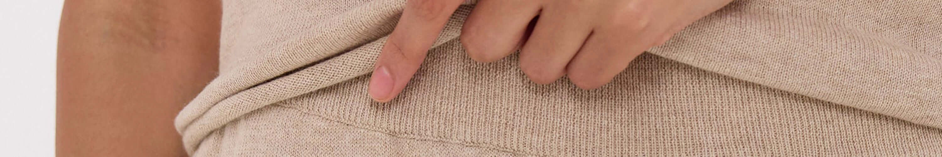 Alt Tag: Cloth & Co beige knit fabric close-up with hand, showcasing timeless Australian sustainable clothing materials
