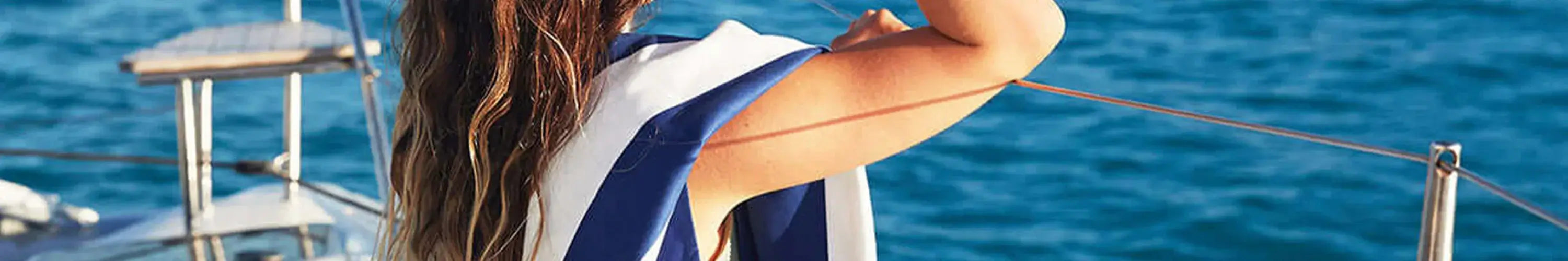 Alt Tag: Dock & Bay quick-dry beach towel draped over woman on boat by the sea, lightweight compact travel-friendly towel