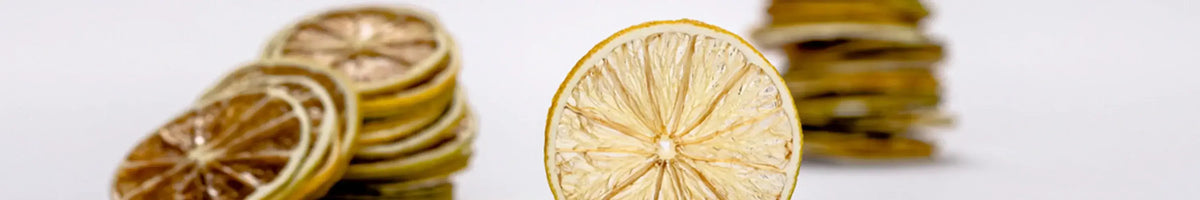Parched dehydrated lemon and lime slices stacked on a white surface, brand banner
