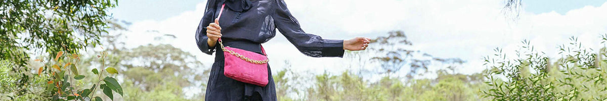 Arlington Milne pink leather crossbody bag worn with black outfit outdoors, premium ethically sourced women’s accessory