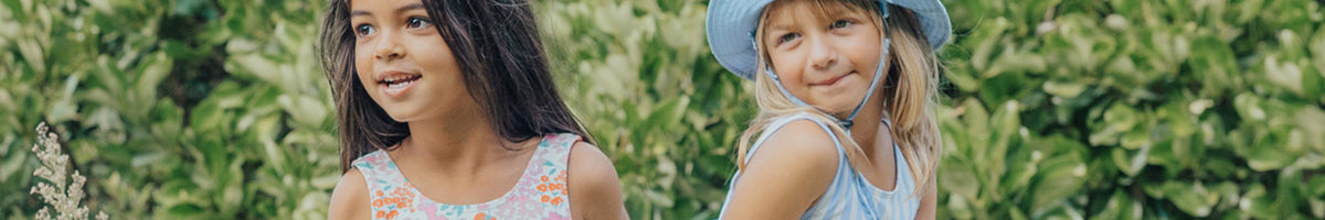 Crywolf kids outdoor gear in bold prints, featuring two children in stylish waterproof rainwear for rainy-day adventures
