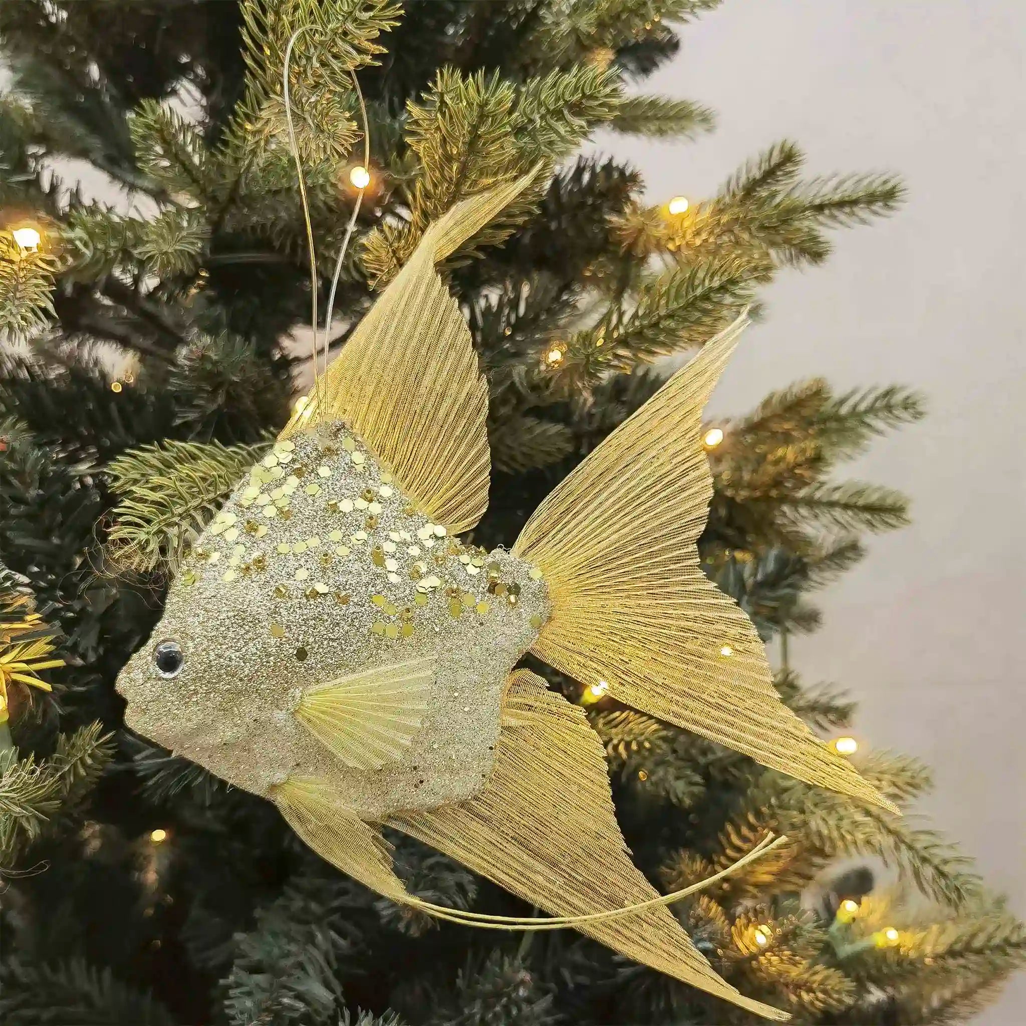 Decorative fish ornament with glittery body on a Christmas tree.
