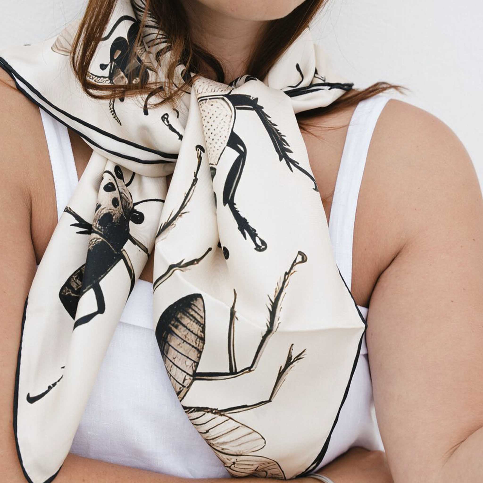 Alt Tag: Artifact Square Silk Scarf - Bugs worn as a neck scarf, cream silk twill with entomology insect print and hand-rolled hem