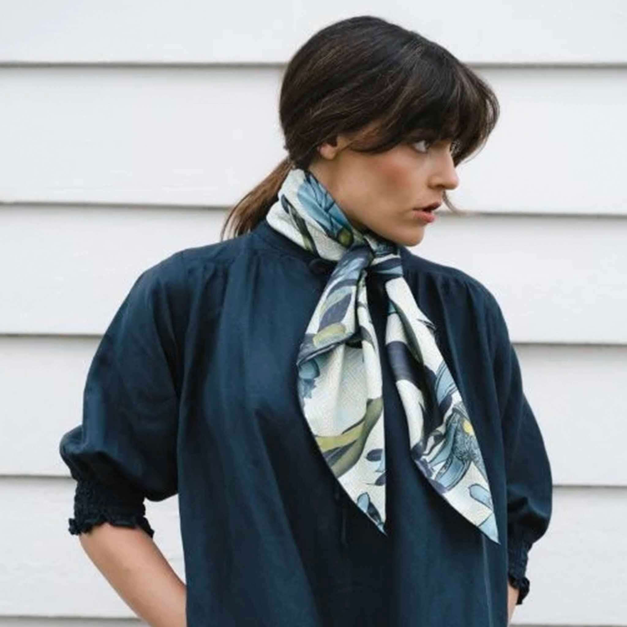 Alt Tag: Artifact Square Silk Scarf - Eos worn around neck, blue and yellow botanical silk twill scarf on model