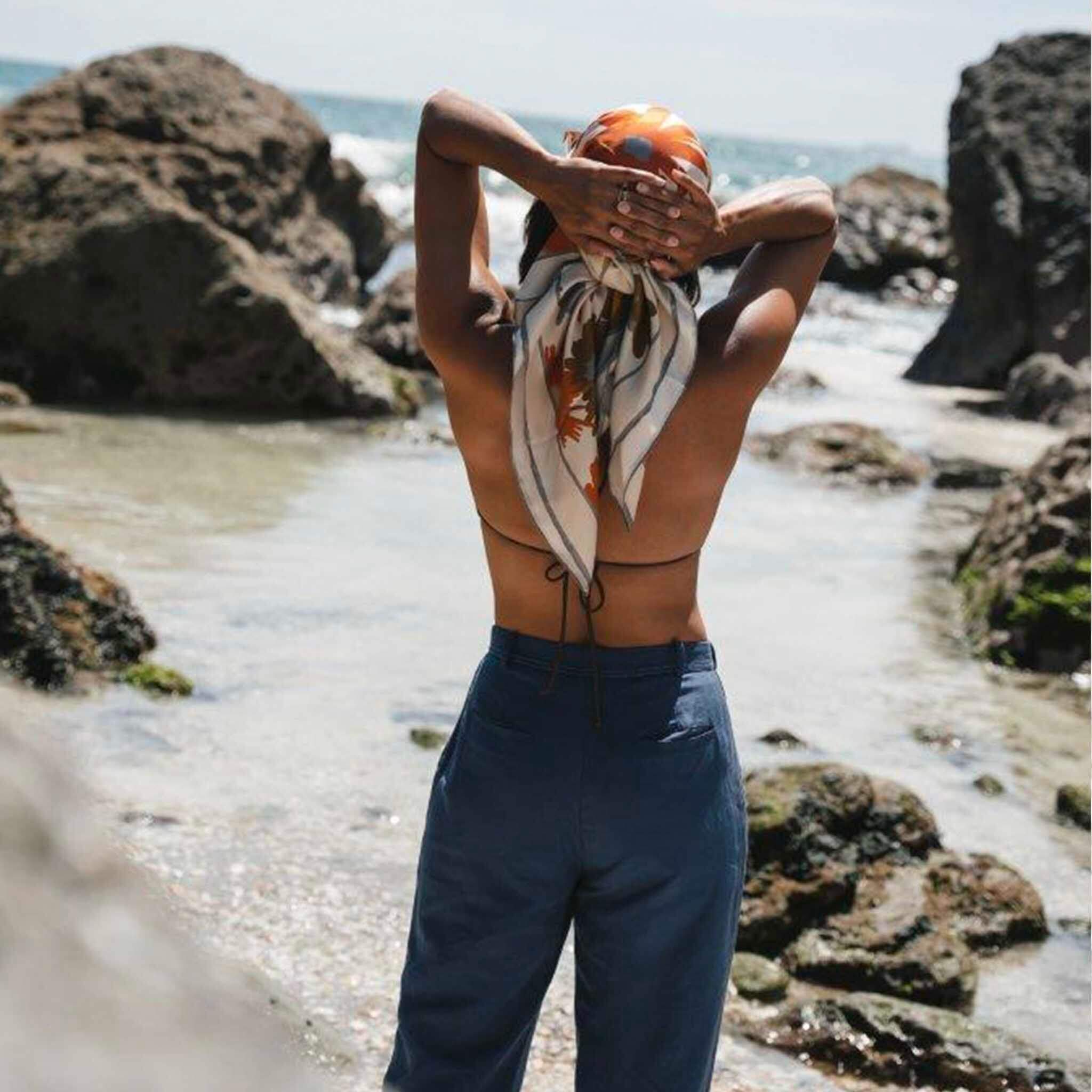 Alt Tag: Artifact Square Silk Scarf - Floravive worn as headscarf on beach, abstract floral silk twill in vibrant summer hues