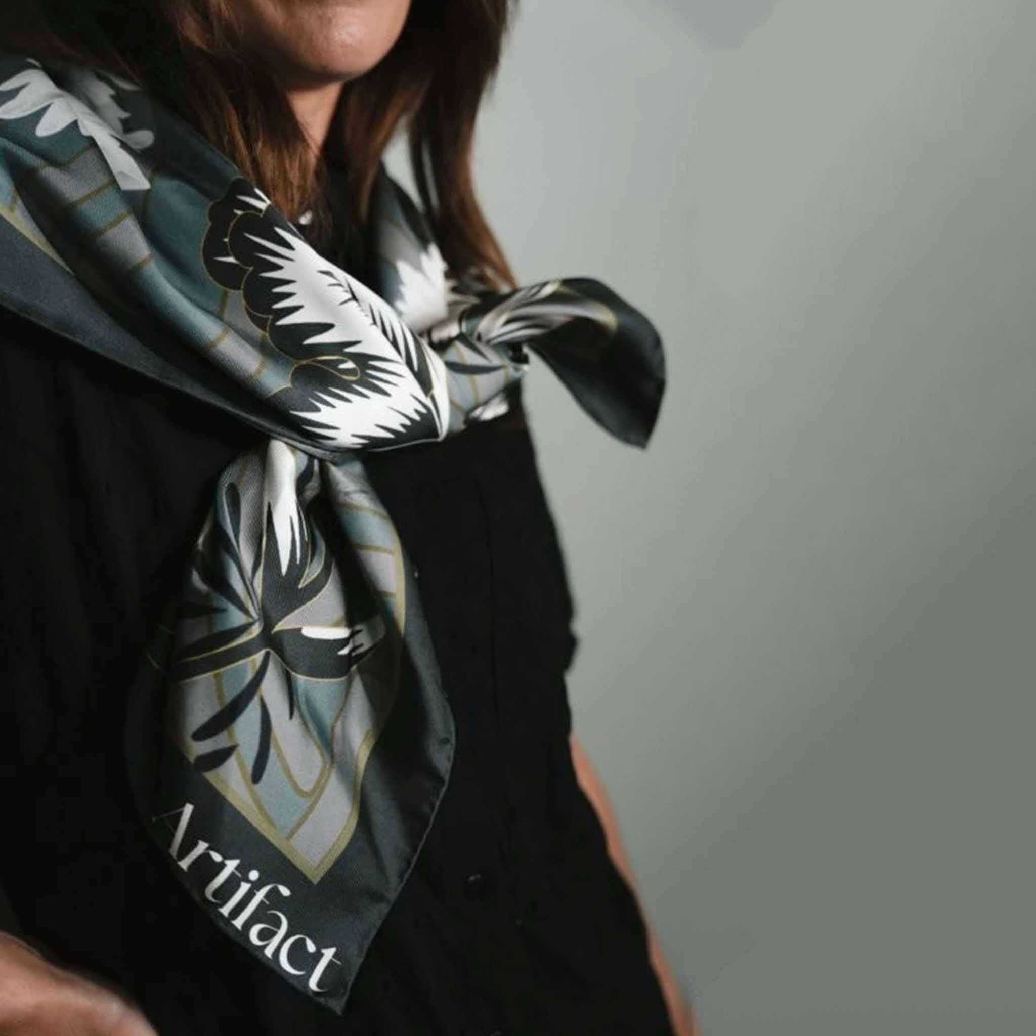 Alt Tag: Artifact Square Silk Scarf - Silva Noire tied at neck, green geometric base with ivory black floral botanical print