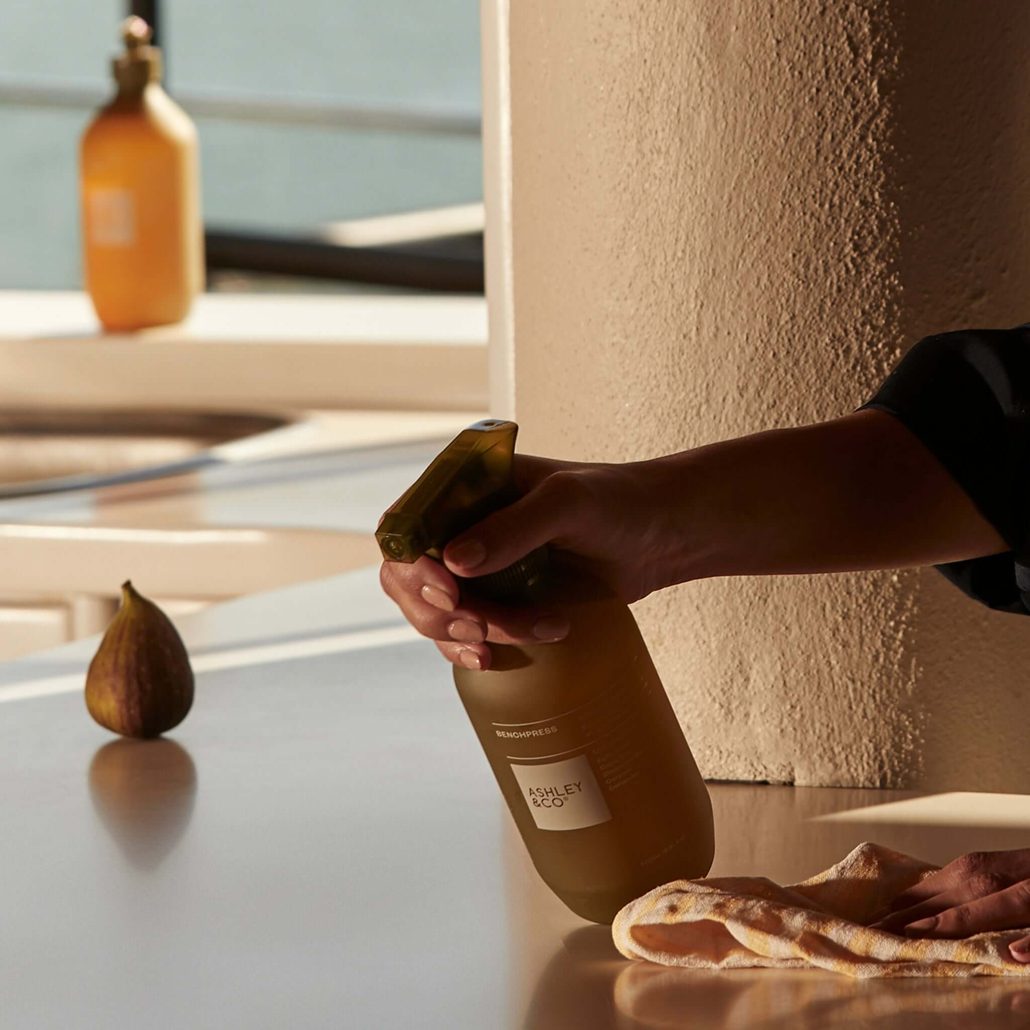 Alt Tag: Ashley & Co Benchpress Surface Cleaner - Lotus Leaf & Lustre spray bottle used to clean countertop, biodegradable essential oils