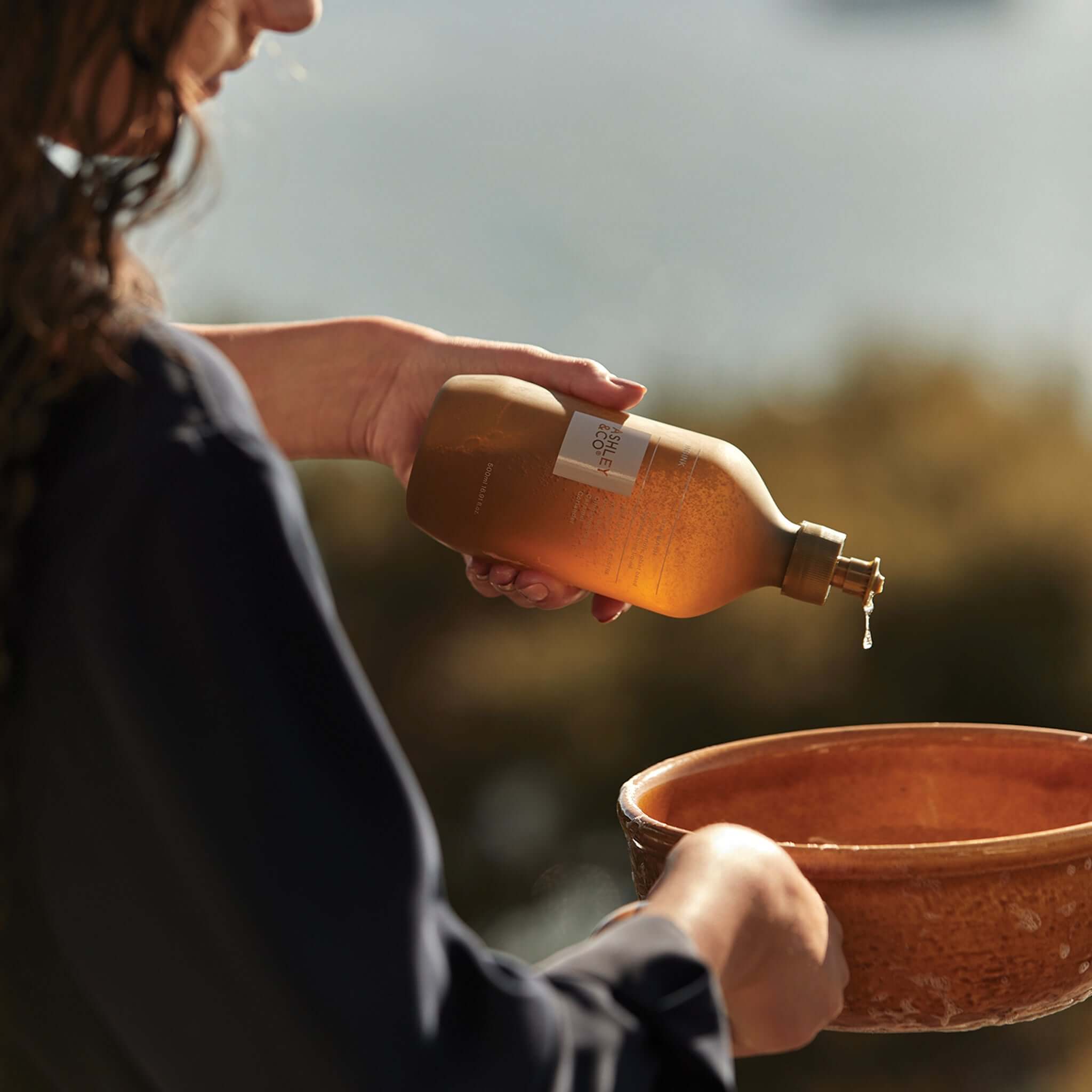 Alt Tag: Ashley & Co In Sink Dishwashing Liquid - Lotus Leaf & Lustre bottle dispensing eco-friendly botanical soap into dish bowl