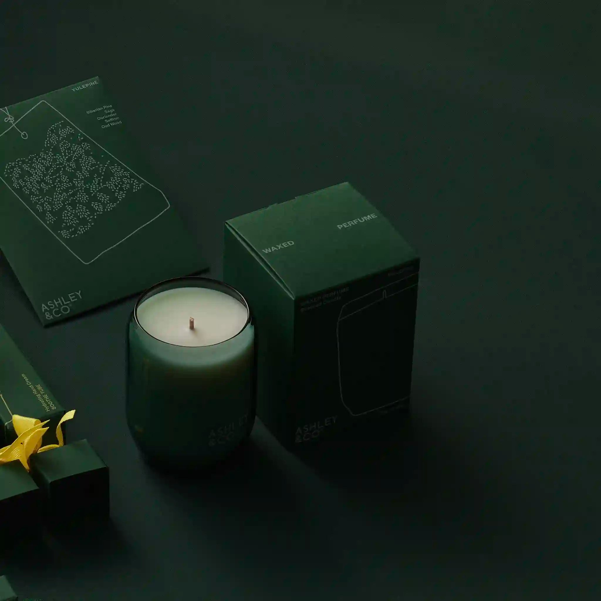 Green candle and packaging on a dark background