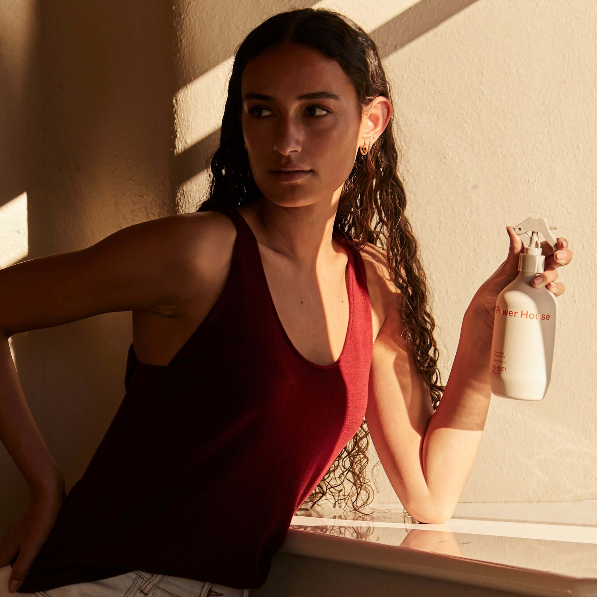 Alt Tag: Ashley & Co Power House Room Mist spray bottle held by woman in sunlight, home fragrance mist for freshening rooms and car