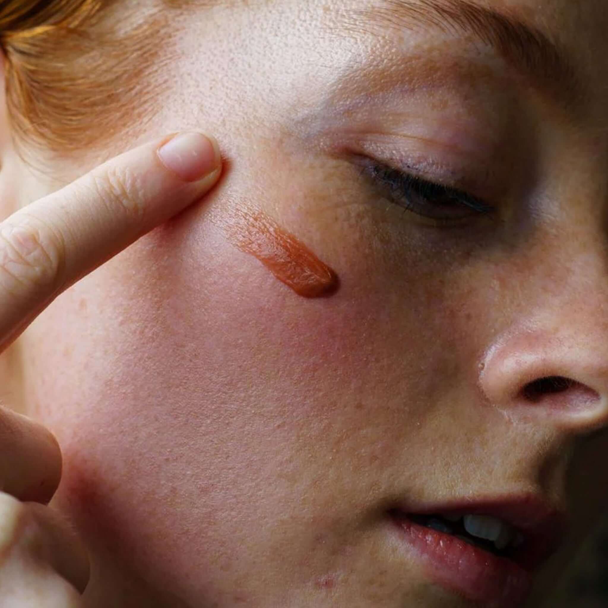 Alt Tag: Ashley & Co Tint Me Lip Punch Lip Balm - Coffee Date swatch applied to cheek, warm natural tint close-up