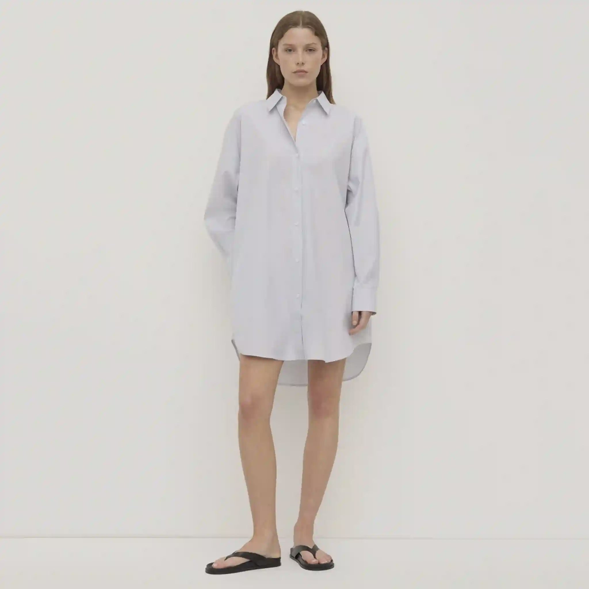 Woman wearing a light blue shirt dress on a white background