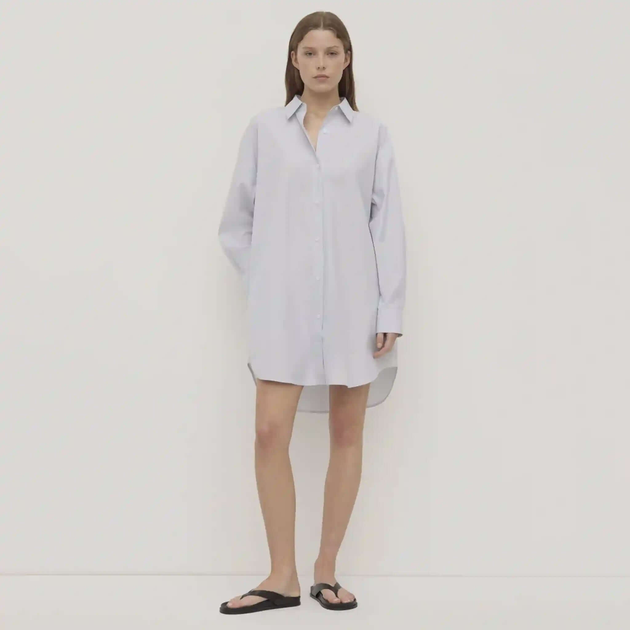 Woman wearing a light blue shirt dress on a white background