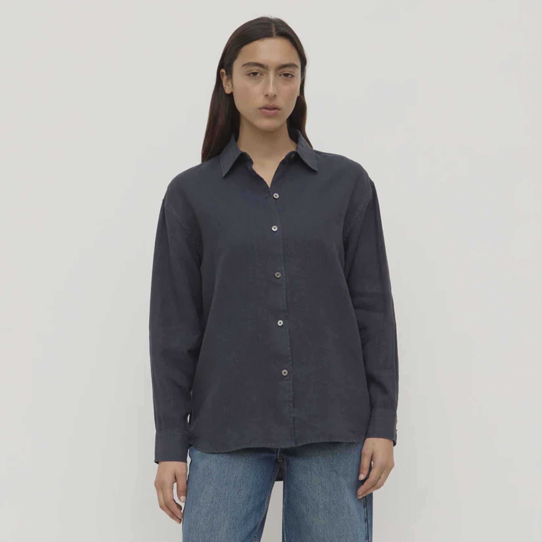 Person wearing a dark blue shirt and jeans on a plain background
