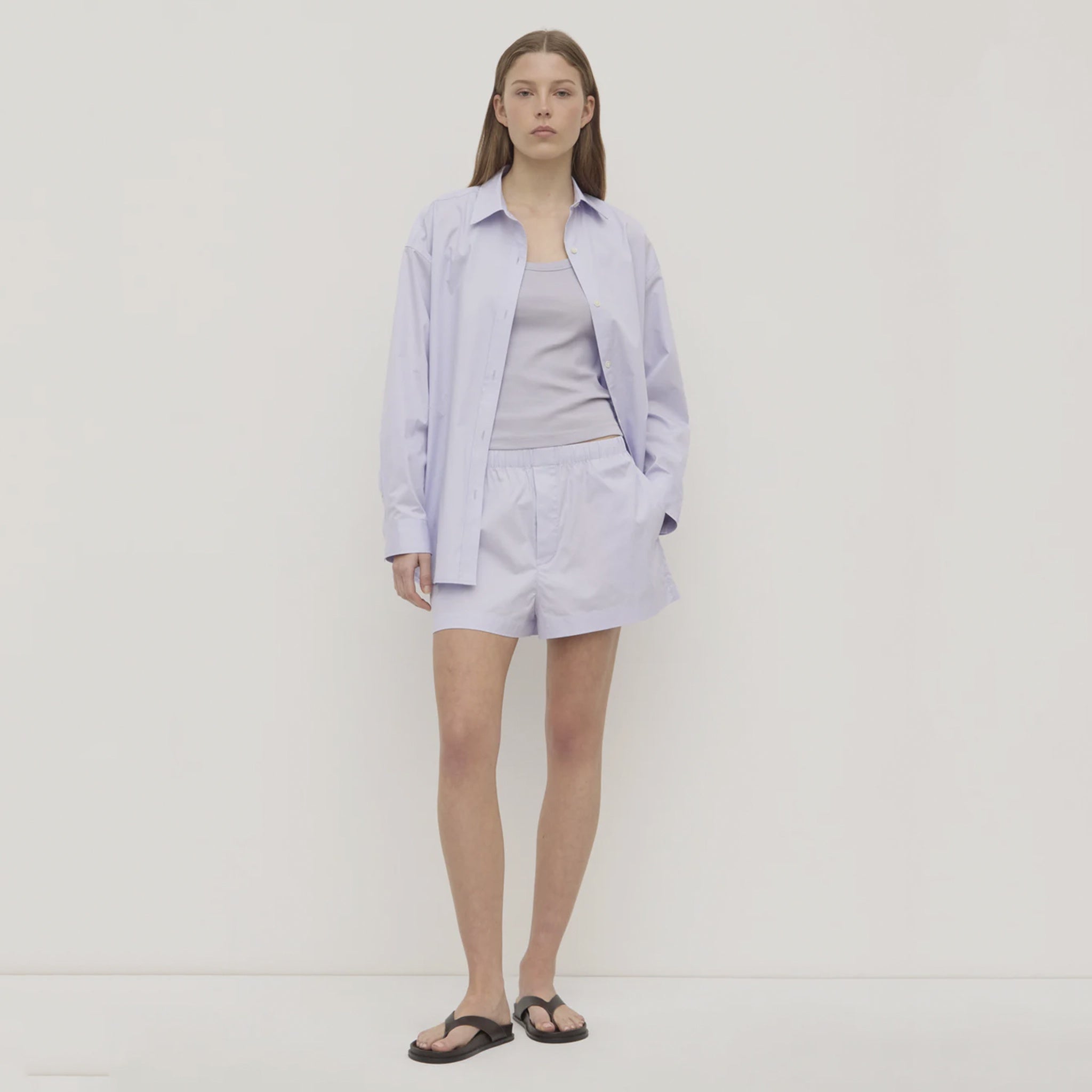 Woman wearing a light purple outfit on a plain background