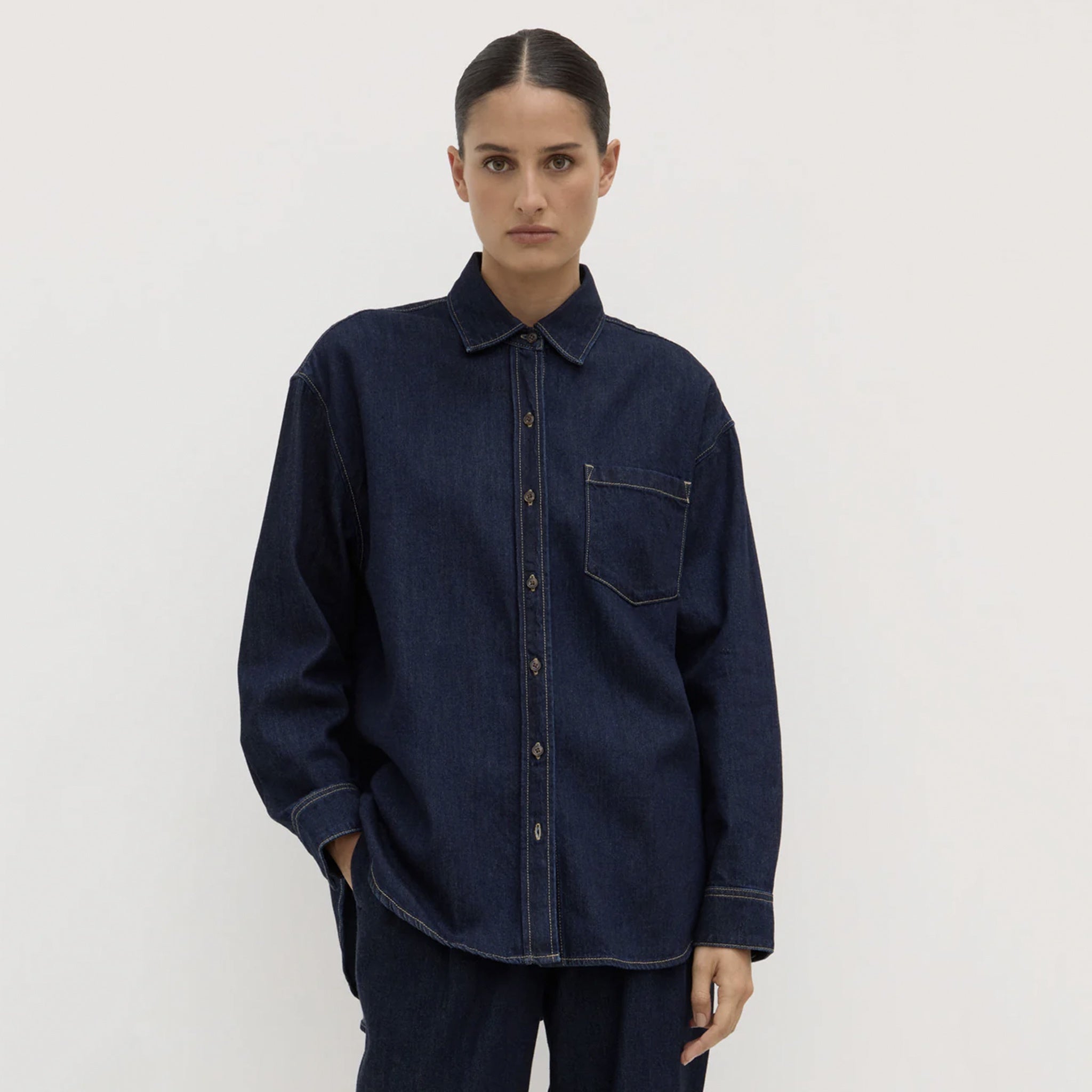 Person wearing a dark blue denim shirt on a plain background