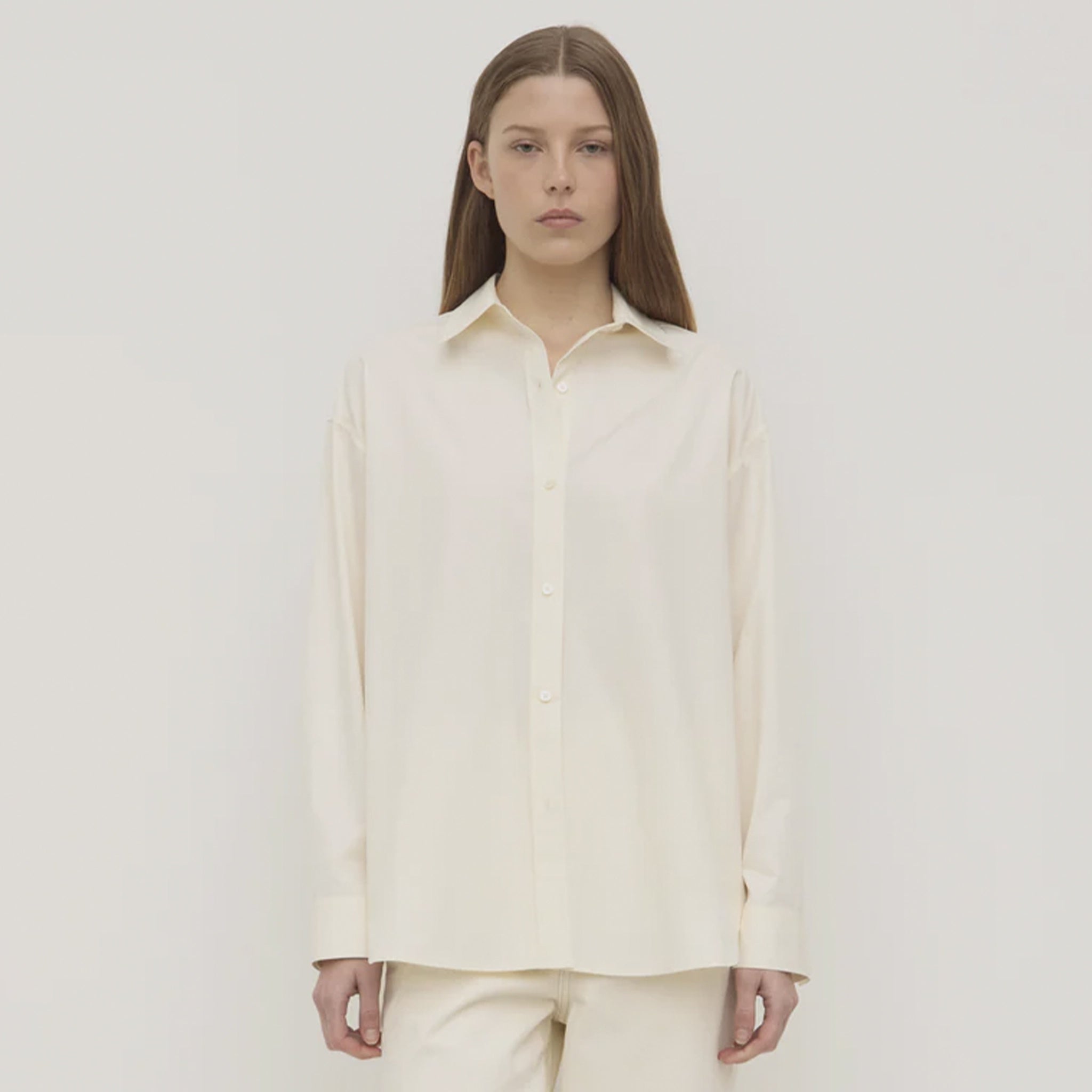 Person wearing a white shirt against a plain background