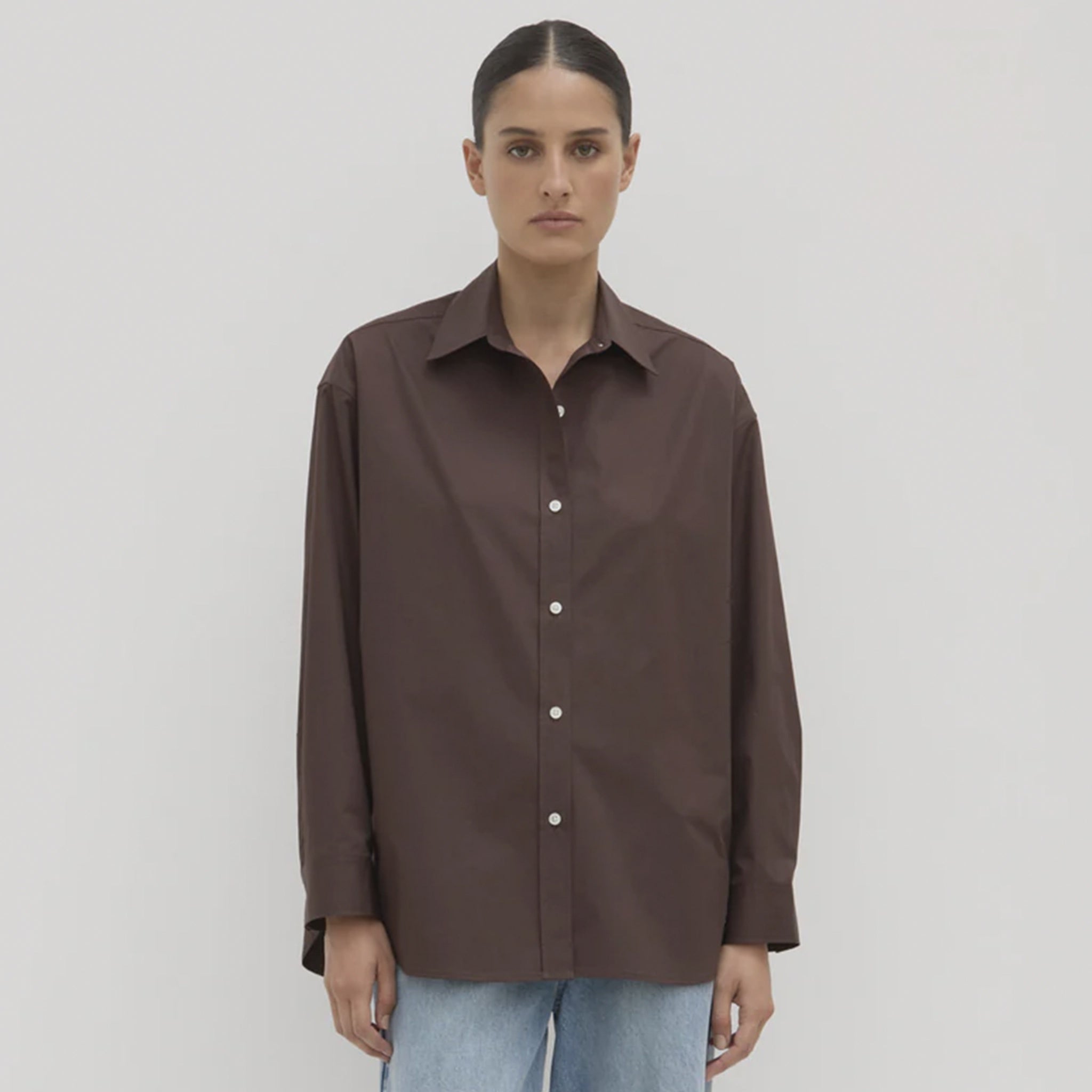 Person wearing a brown shirt on a plain background