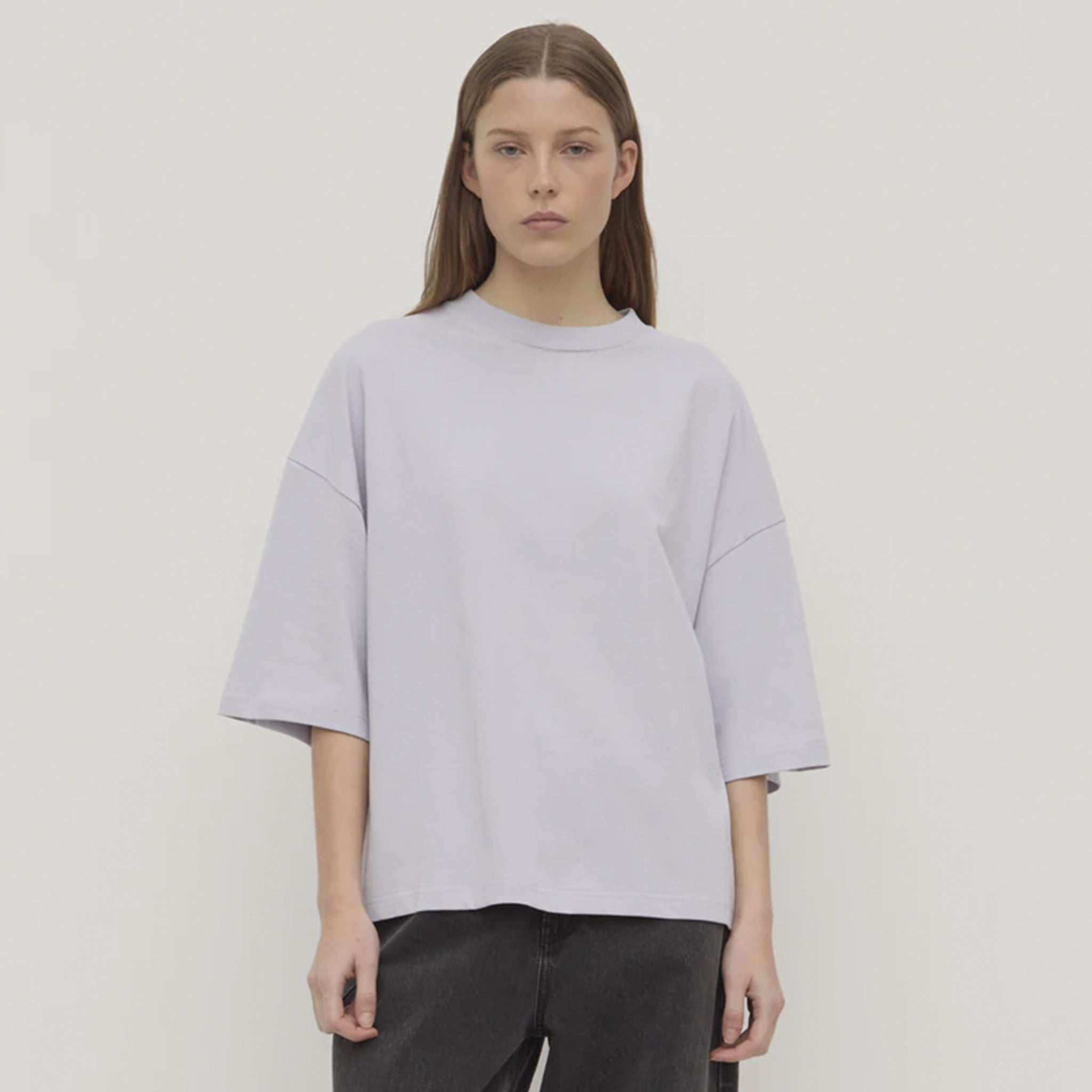 Person wearing a lilac top and dark pants against a white background