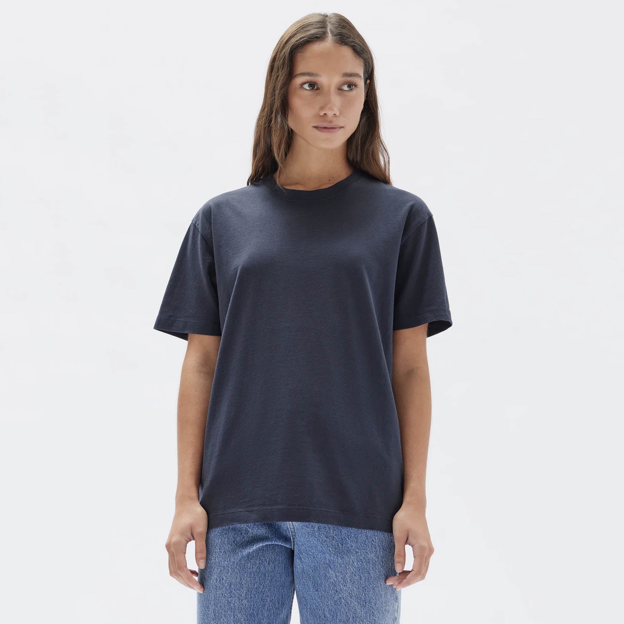 A woman wearing a true navy blue crew neck t-shirt paired with light blue jeans.