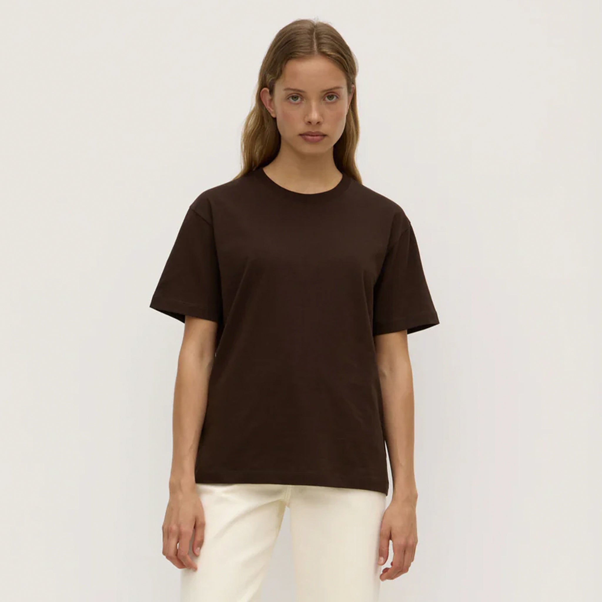 Person wearing a brown t-shirt and white pants on a plain background
