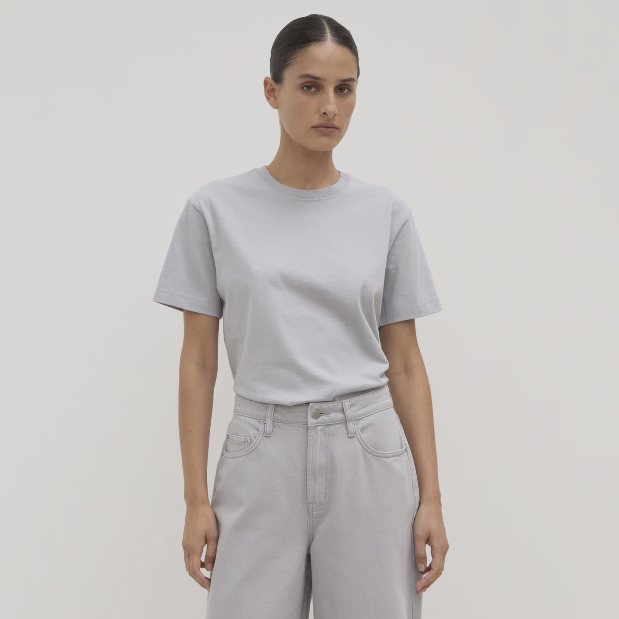 Person wearing a light gray t-shirt and light gray pants on a plain background