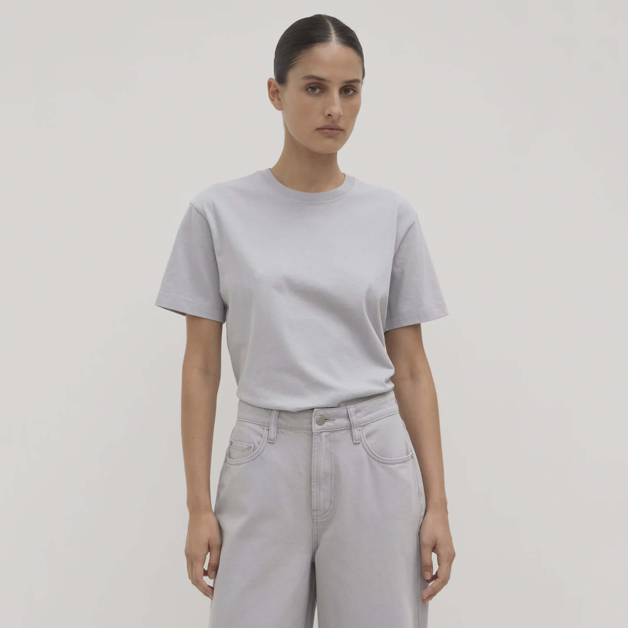 Person wearing a light gray t-shirt and light gray pants on a plain background