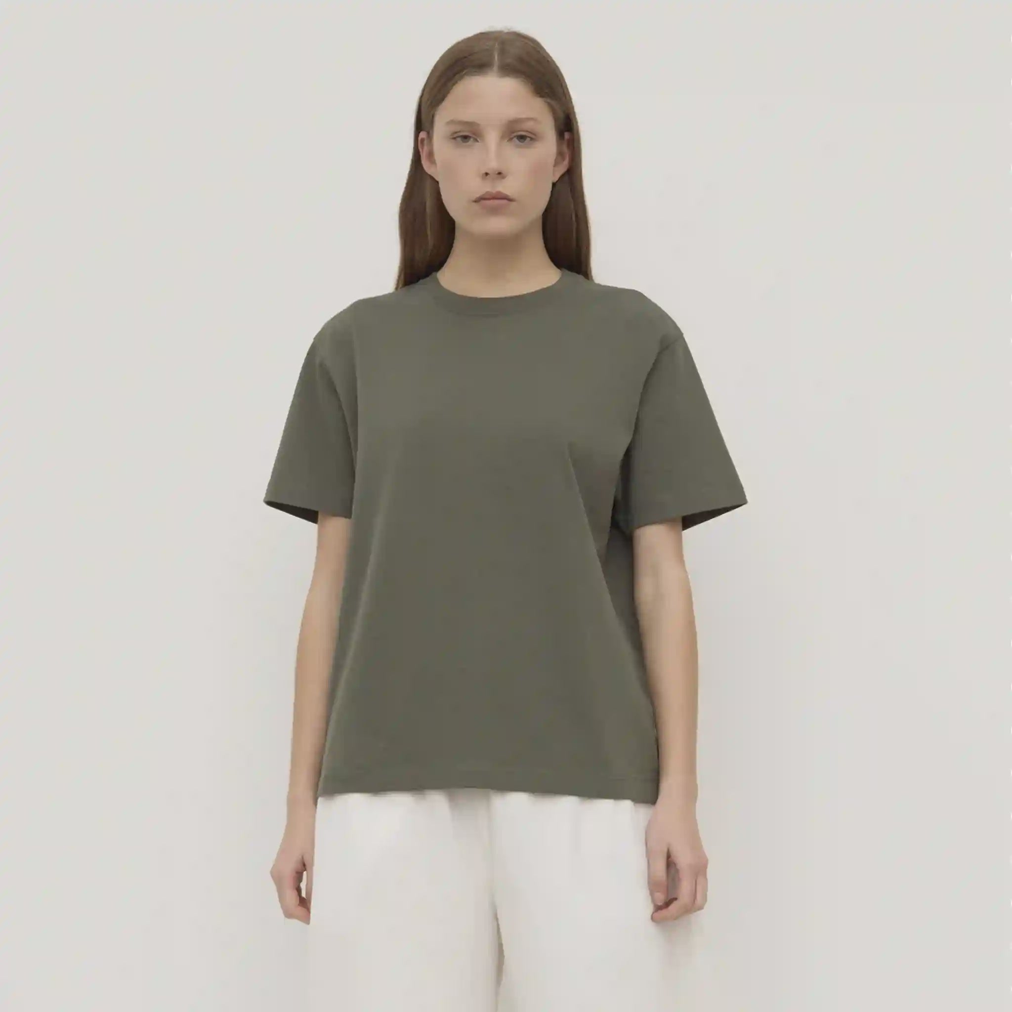 Person wearing a green t-shirt and white pants against a plain background