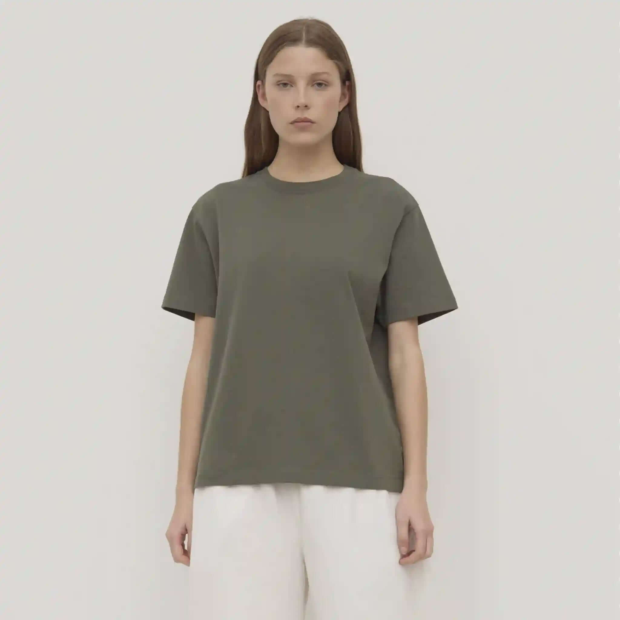 Person wearing a green t-shirt and white pants against a plain background