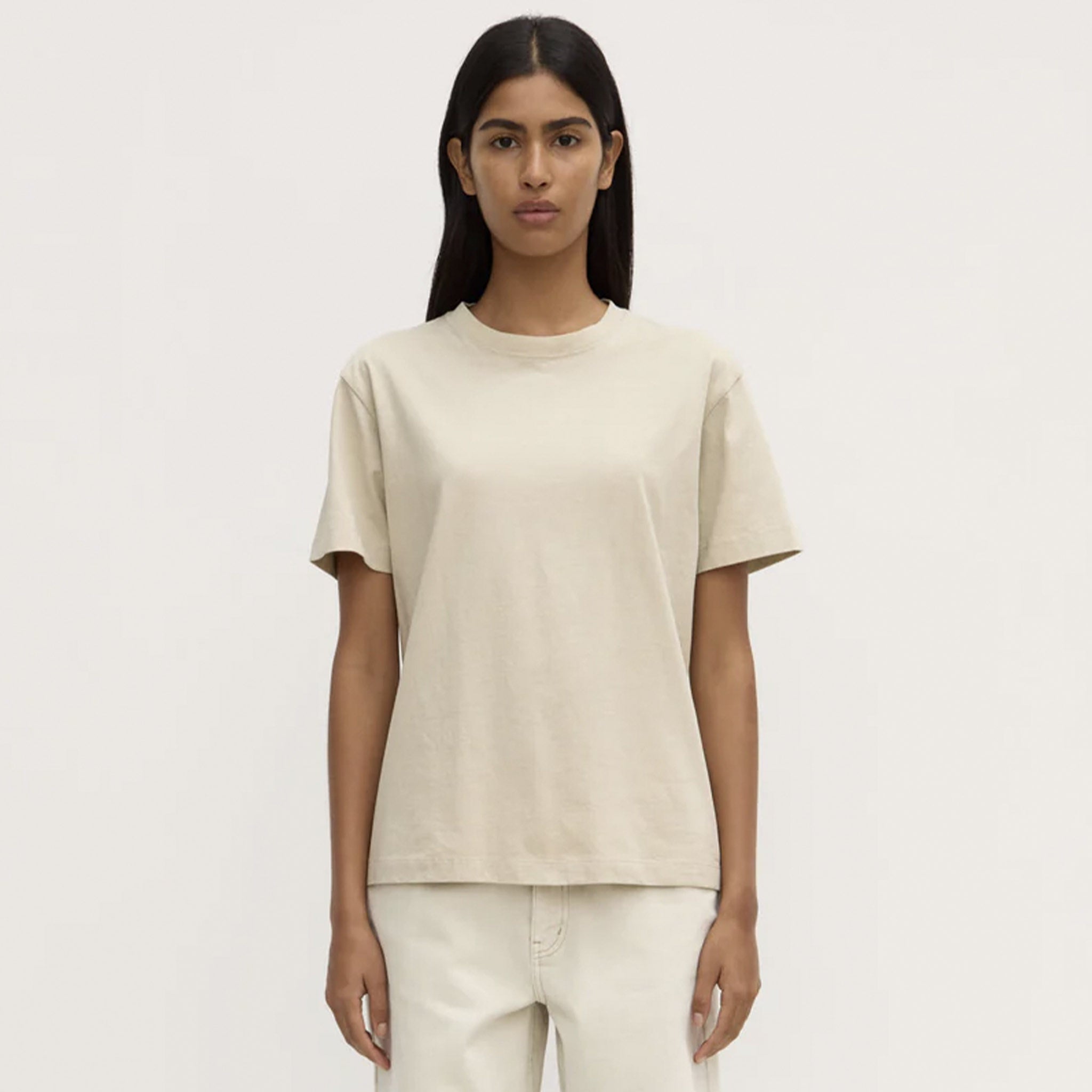 Person wearing a beige t-shirt and pants on a white background