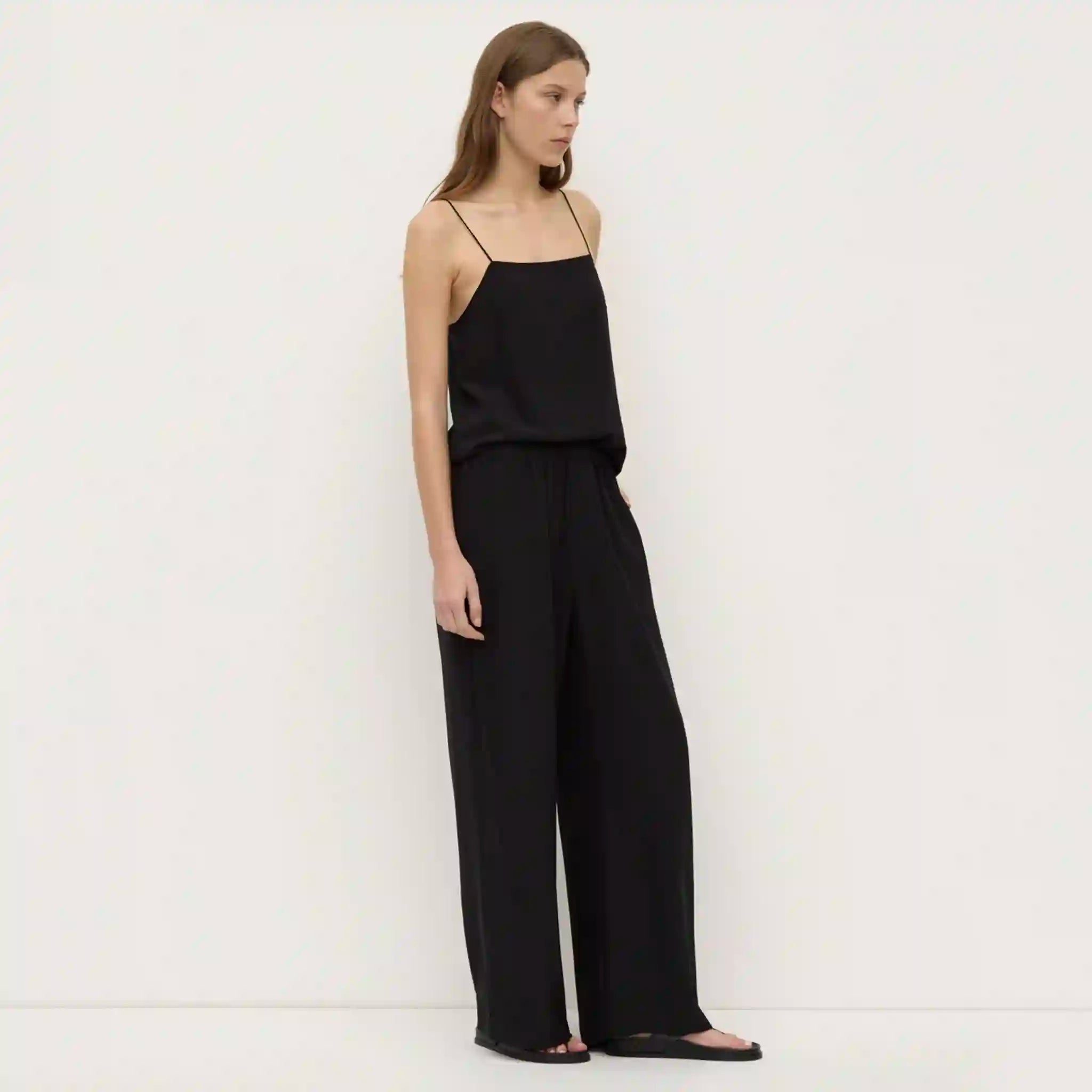 Woman wearing a black jumpsuit against a white background