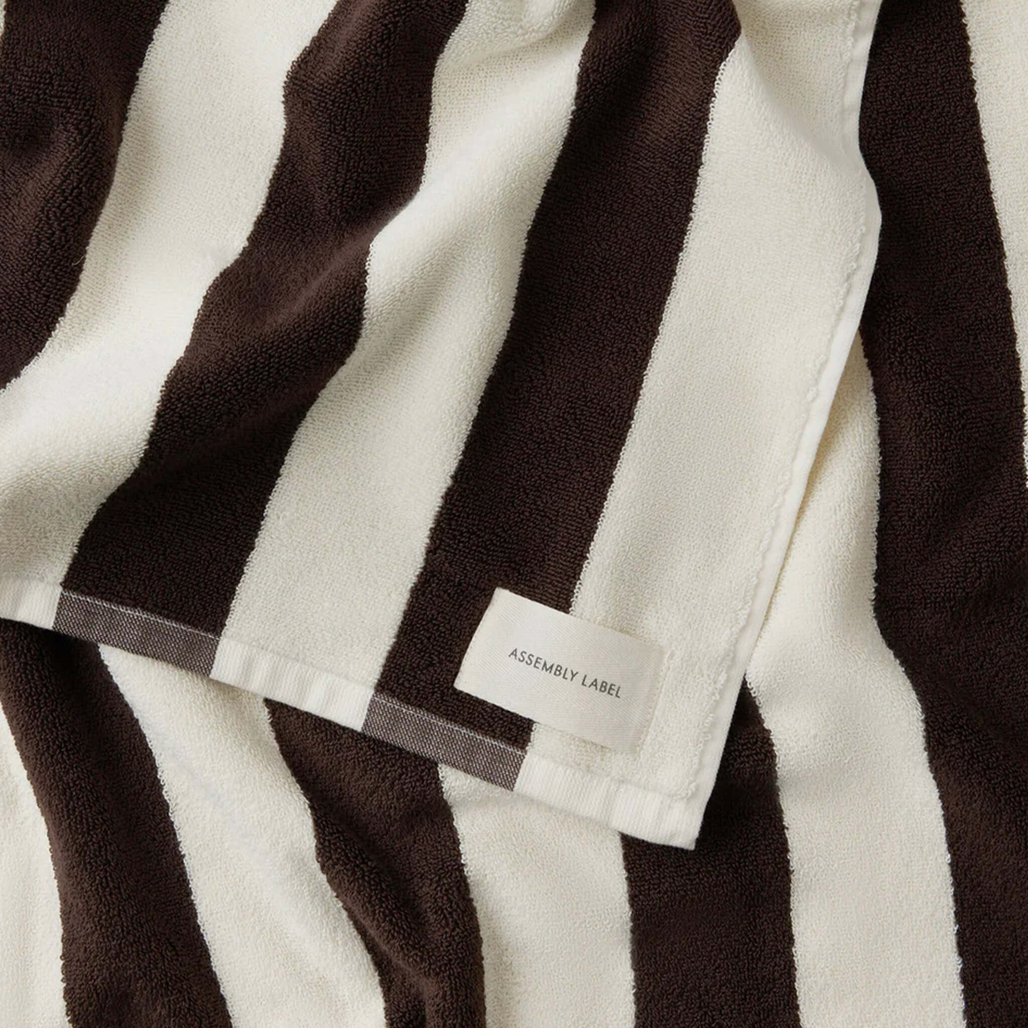 Close-up of a brown and white striped beach towel with a label.