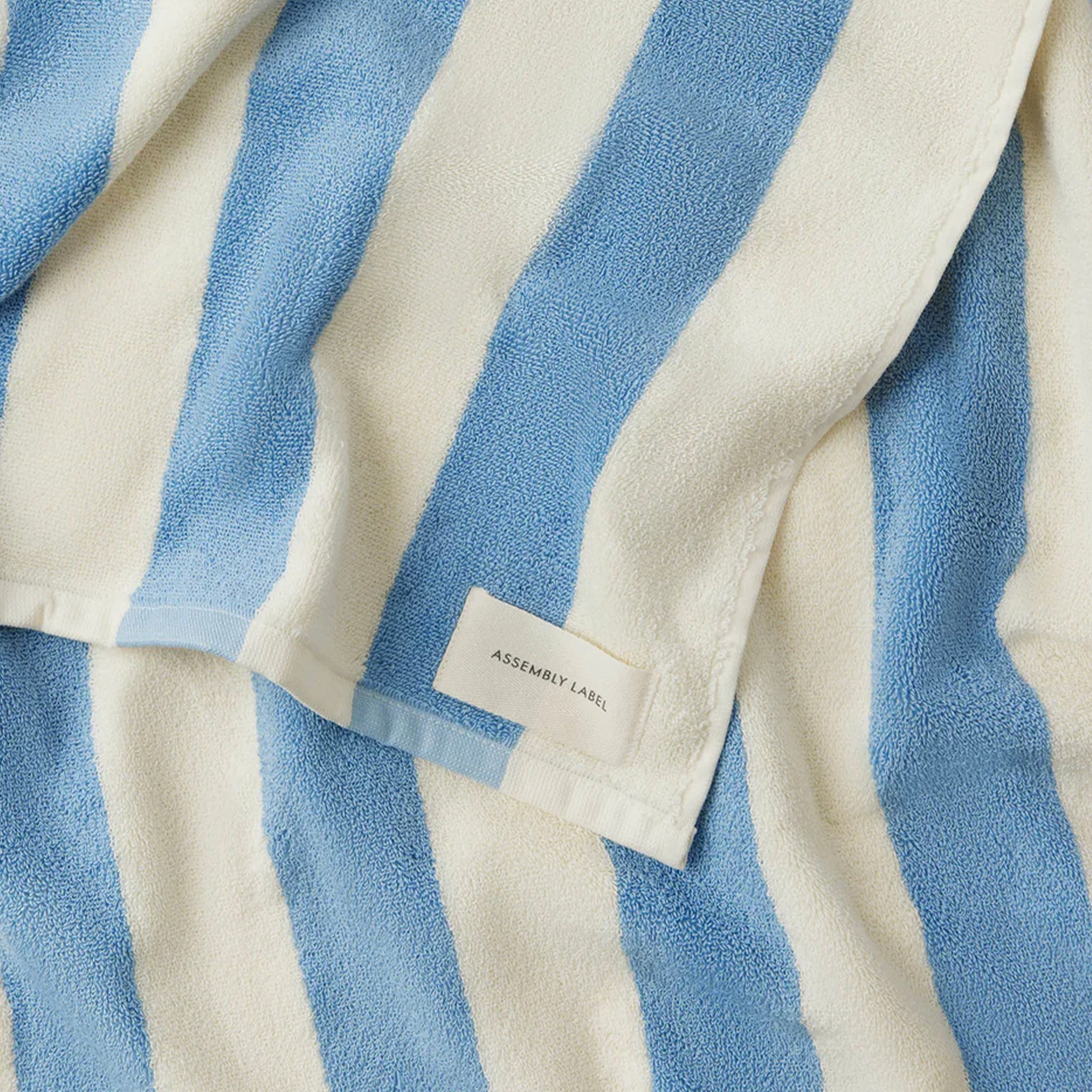 Blue and white striped towel with 'Assembly Label' tag