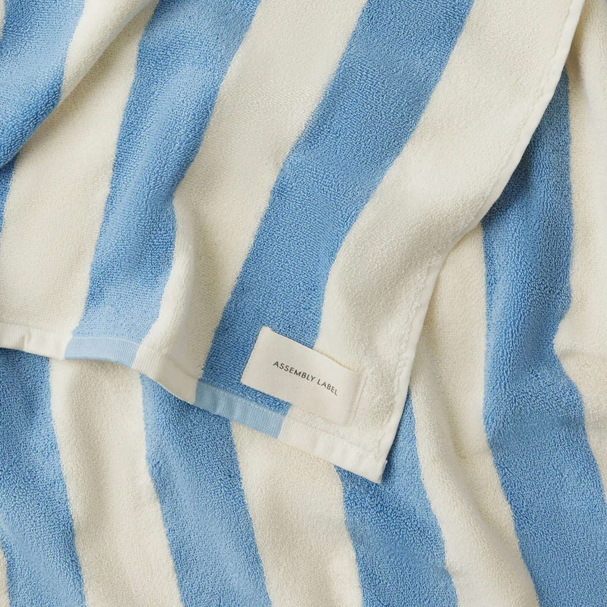 Blue and white striped towel with 'Assembly Label' tag