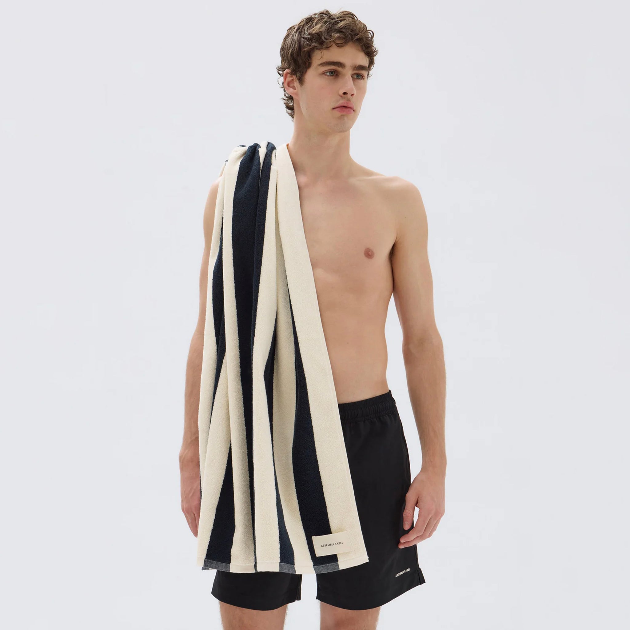Navy and cream striped bath towel draped over a man's shoulder.
