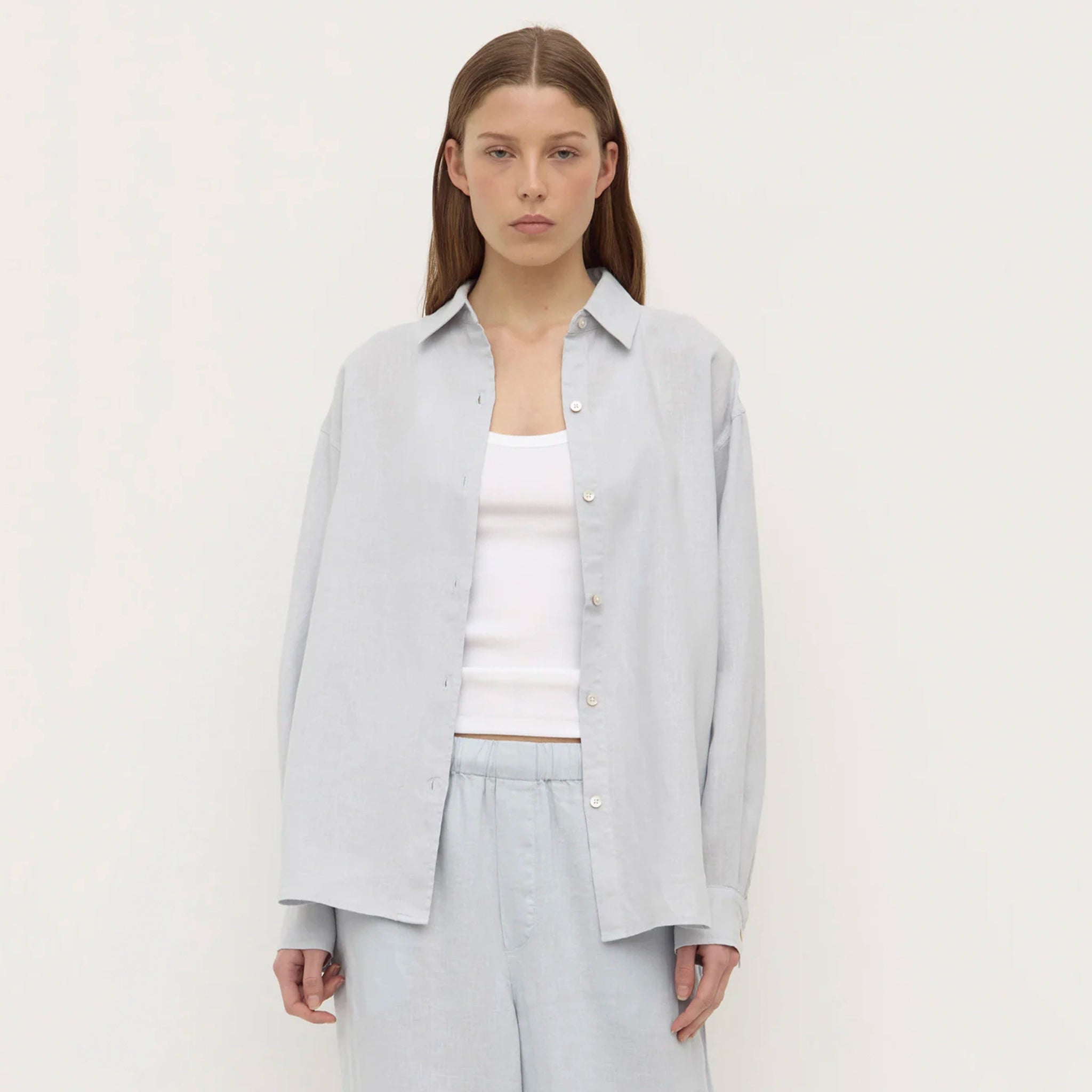 Person wearing a light gray shirt and pants on a white background