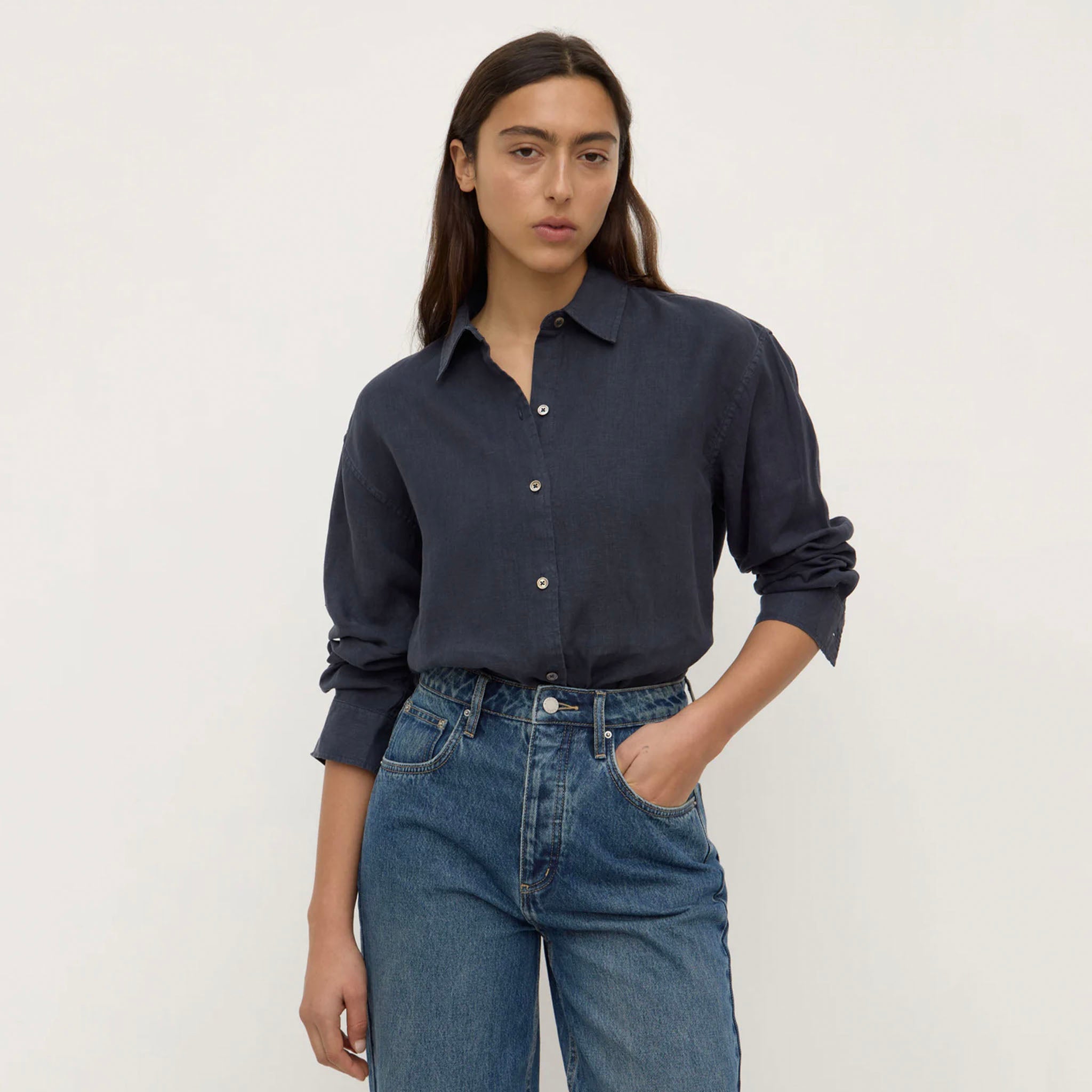 Person wearing a navy shirt and blue jeans against a plain background