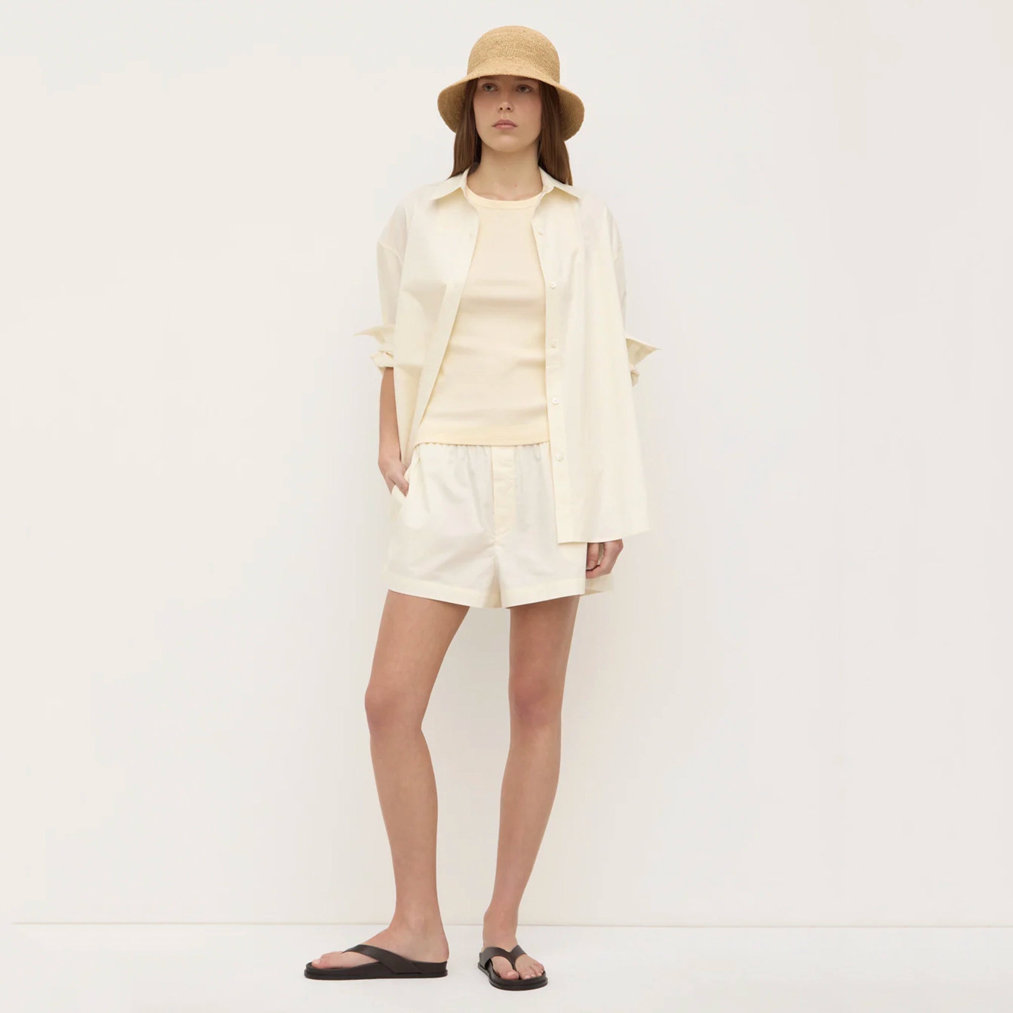 Person wearing a cream-colored outfit with a hat on a white background