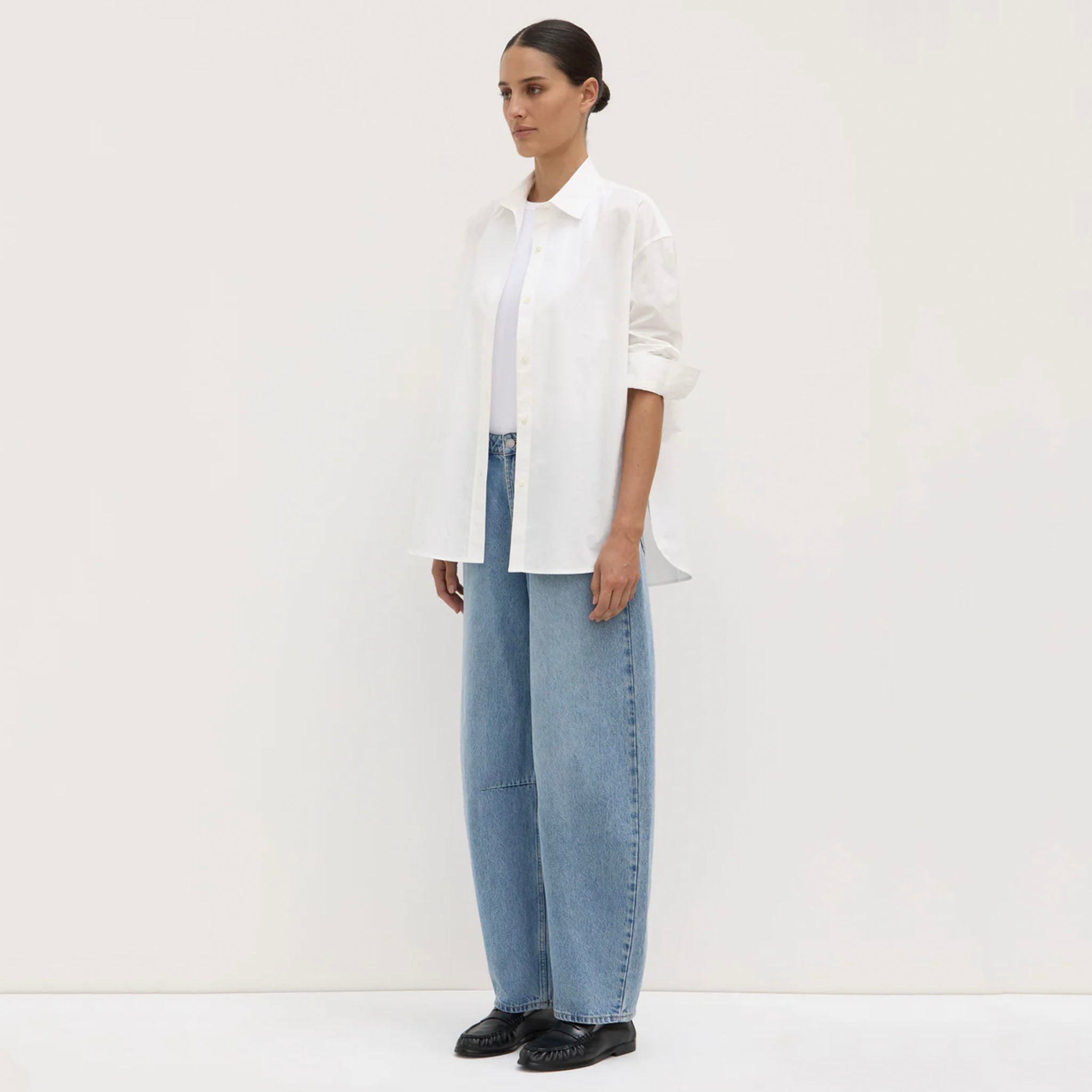 Person wearing a white shirt and light blue jeans on a white background