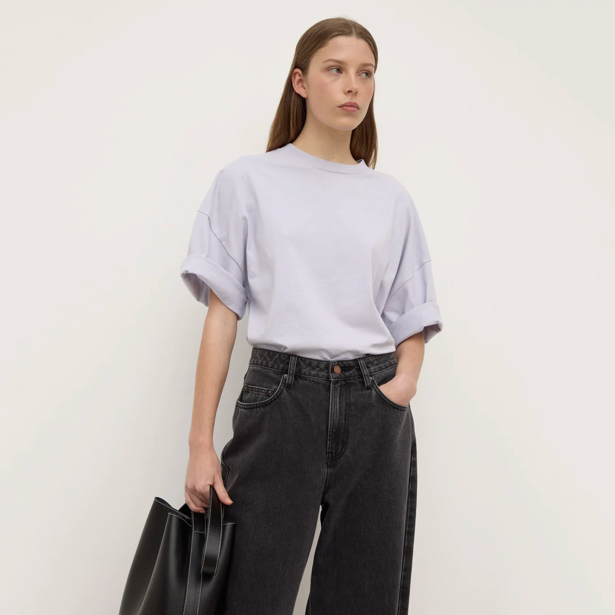 Person wearing a lilac top and dark pants against a white background