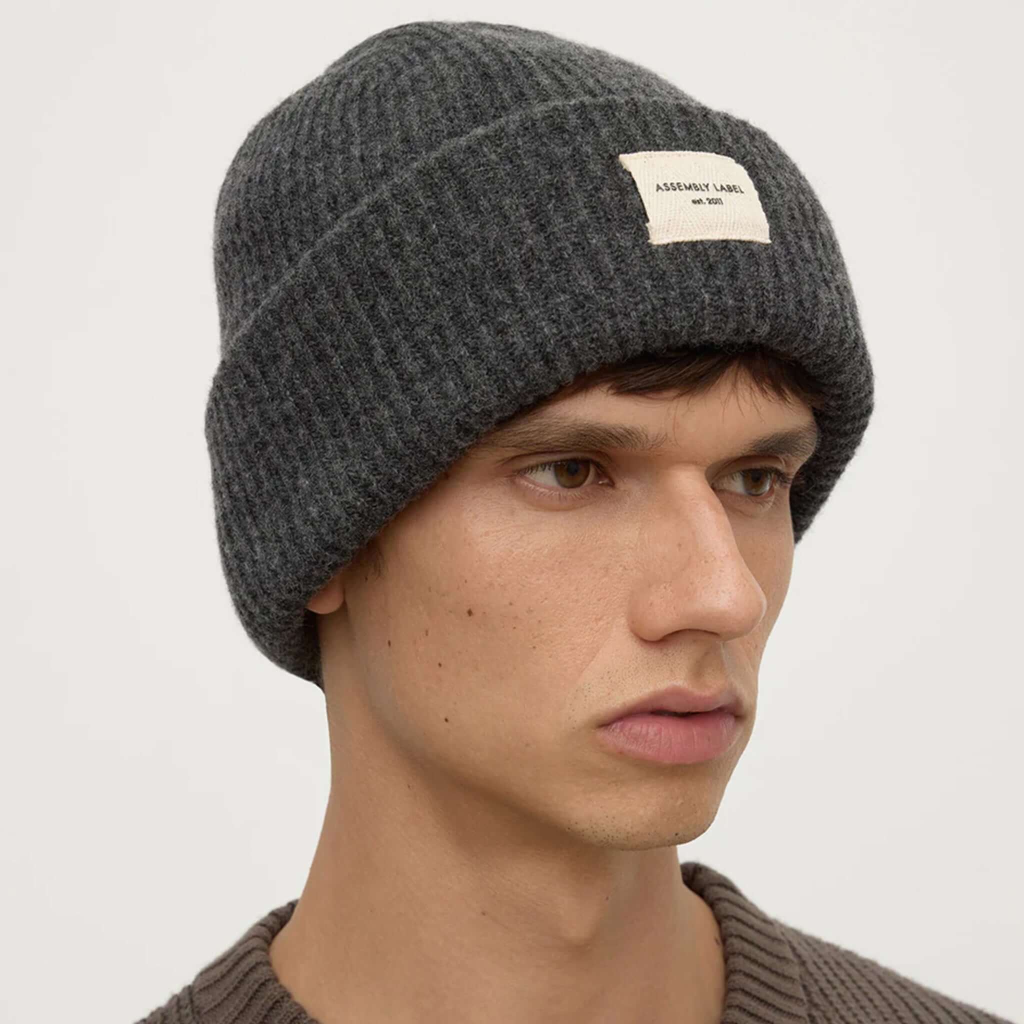 Assembly Label Merino Wool Rib Beanie - Charcoal Marle worn by model, showcasing its warmth and style.