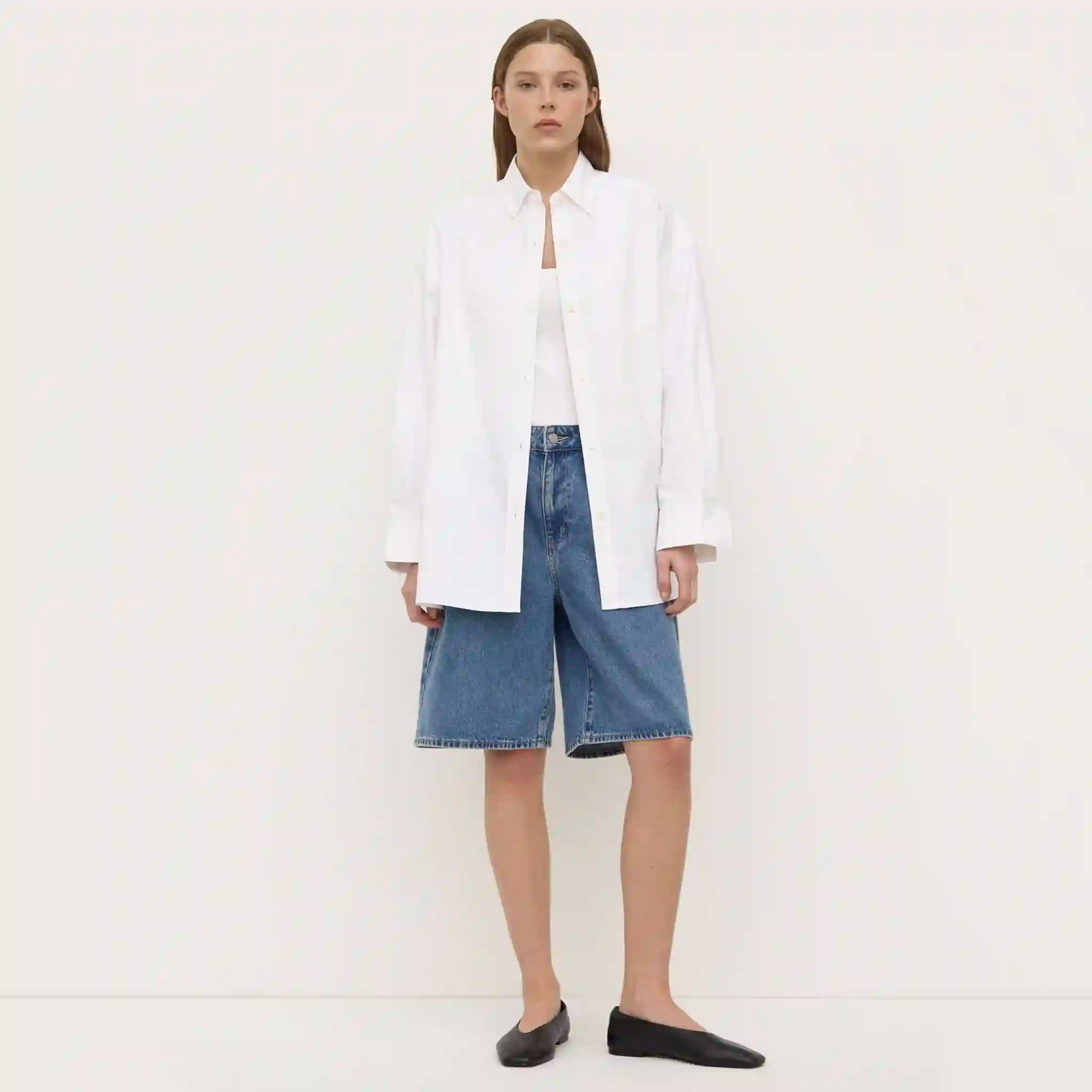 Person wearing a white shirt and blue jeans on a plain background