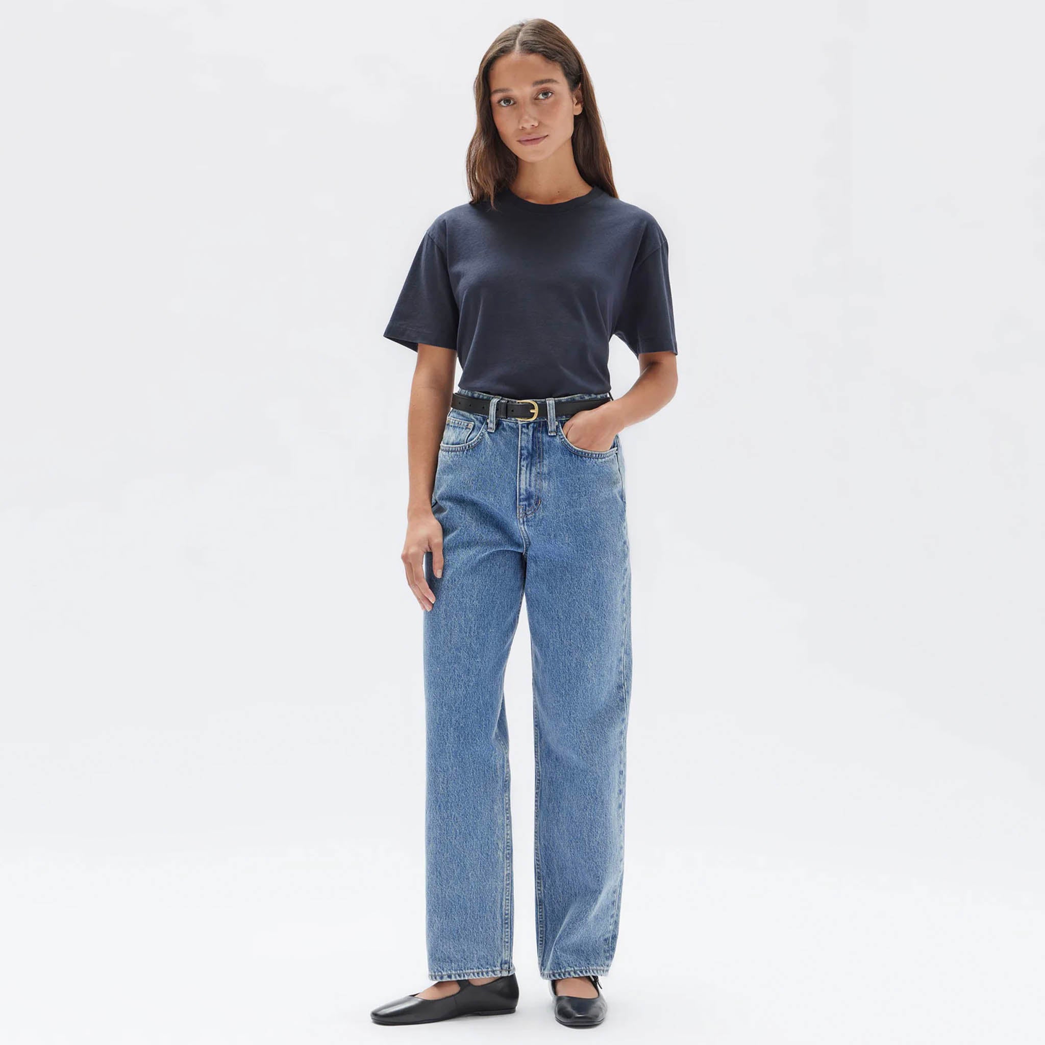 A woman wearing a true navy blue crew neck t-shirt paired with light blue jeans.