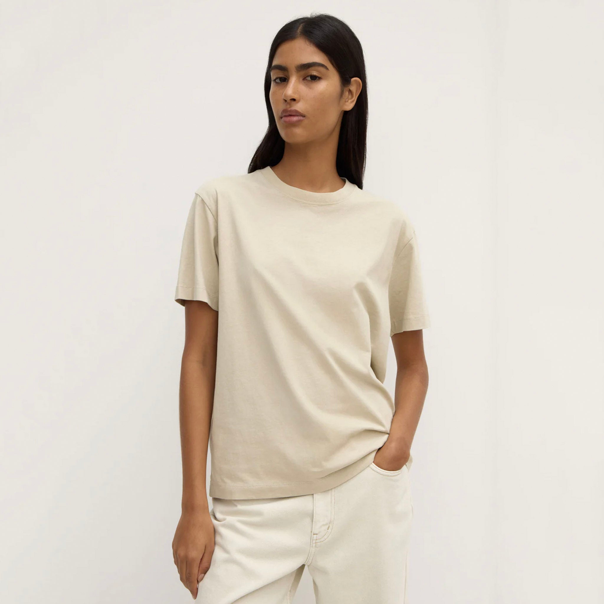 Person wearing a beige t-shirt and pants against a white background